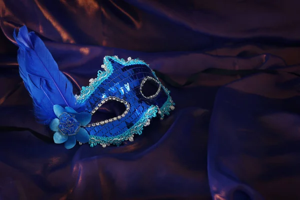 Photo of elegant and delicate blue Venetian mask over purple silk background — 图库照片