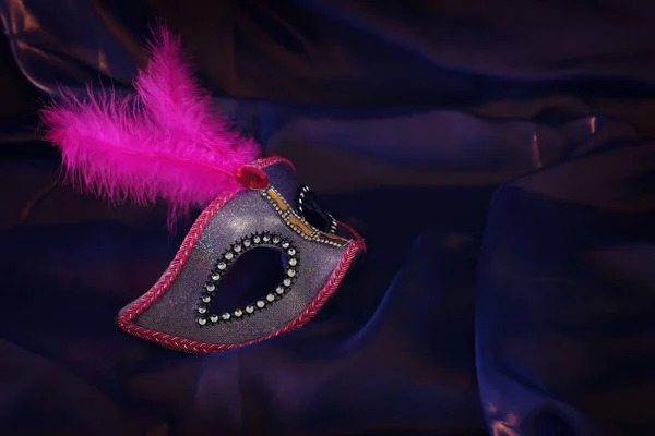 Zdjęcie eleganckiej i delikatnej różowej weneckiej maski na fioletowym tle jedwabiu — Zdjęcie stockowe