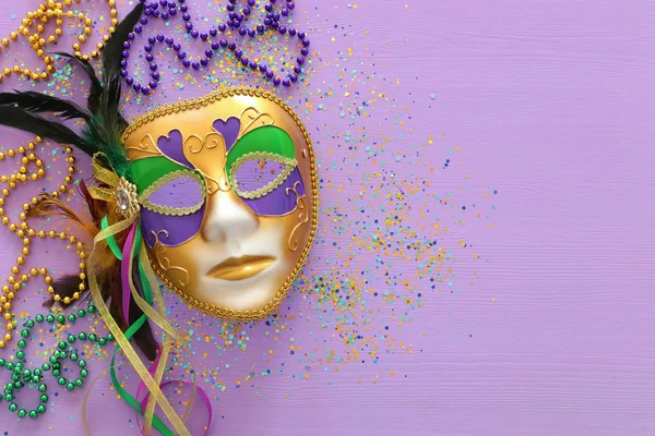 Świąteczny obraz maskarady Mardi Gras, weneckiej maski i koralików na fioletowym tle. widok z góry — Zdjęcie stockowe