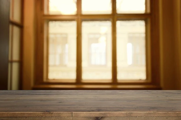 Gambar dari tabel kayu di depan latar belakang cahaya jendela yang kabur abstrak — Stok Foto