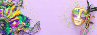 Mardi Gras maskesi, Venedik maskesi ve mor arka planda yelpaze tatili görüntüsü. Yukarıdan görünüm