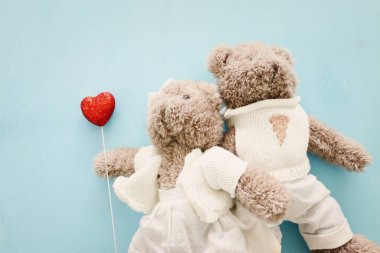 Sevgililer Günü konsepti. Mavi ahşap arka planda kalbi tutan bir çift sevimli oyuncak ayı.