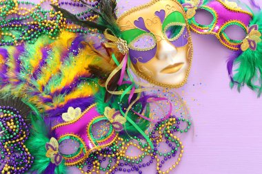 Mardi Gras maskesi, Venedik maskesi ve mor arka planda yelpaze tatili görüntüsü. Yukarıdan görünüm