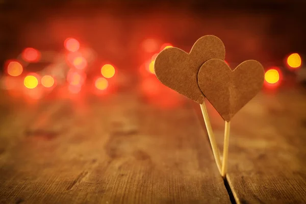 情人节的概念。 木制背景上的两颗心和闪耀的灯光 — 图库照片