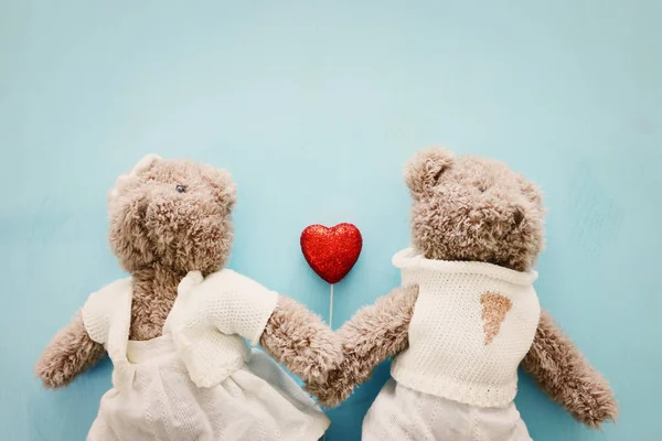 Concetto di San Valentino. Coppia di simpatici orsacchiotti che tengono il cuore su sfondo di legno blu — Foto Stock