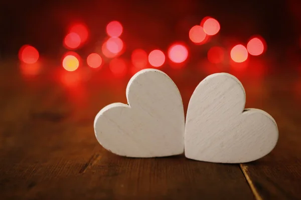 Концепція Дня Святого Валентина. два серця над дерев'яним фоном і блискучі вогні — стокове фото