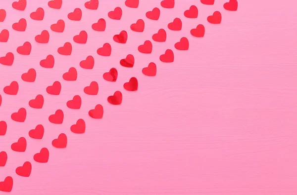 Conceito do dia dos namorados. corações vermelhos sobre fundo rosa de madeira. Composição plana — Fotografia de Stock