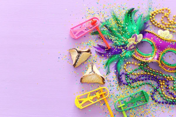 Purim oslava koncepce (židovský karneval dovolená) fialové dřevěné pozadí. Pohled shora, plochý lay — Stock fotografie