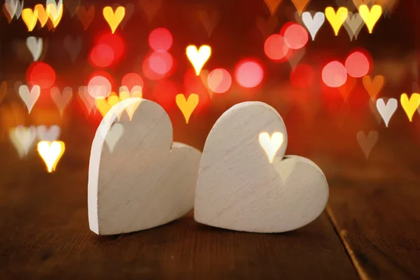 Concepto de San Valentín. dos corazones sobre fondo de madera y luces de brillo — Foto de Stock