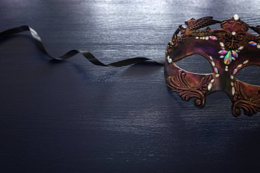 Siyah ahşap arka planda zarif ve narin Venedik maskesinin fotoğrafı.
