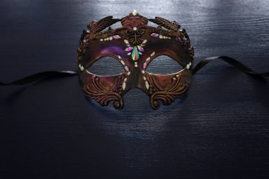 Siyah ahşap arka planda zarif ve narin Venedik maskesinin fotoğrafı.