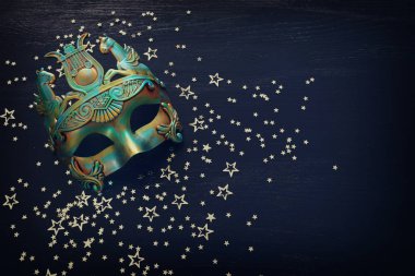 Siyah ahşap arka planda mavi Venedik maskeli zarif ve narin Yunan veya Roma altınlarının fotoğrafı