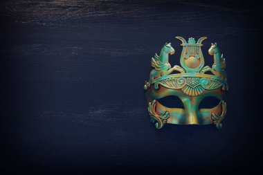 Siyah ahşap arka planda mavi Venedik maskeli zarif ve narin Yunan veya Roma altınlarının fotoğrafı