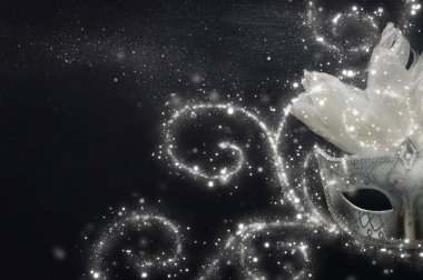 Siyah ahşap arka planda zarif ve narin beyaz Venedik maskesinin fotoğrafı.