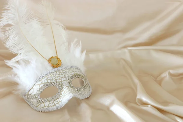 Foto van elegante en delicate witte Venetiaanse masker over witte zijde achtergrond — Stockfoto