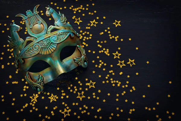 Siyah ahşap arka planda mavi Venedik maskeli zarif ve narin Yunan veya Roma altınlarının fotoğrafı