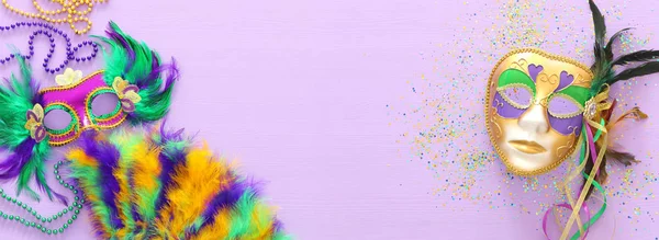 Wakacyjny obraz maskarady Mardi Gras, weneckiej maski i wentylatora na fioletowym tle. widok z góry — Zdjęcie stockowe