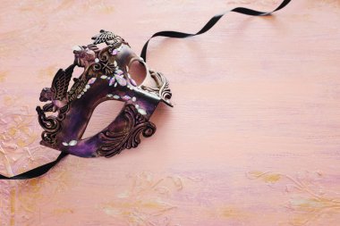 Pastel ahşap arka planda zarif ve narin mor Venedik maskesi.