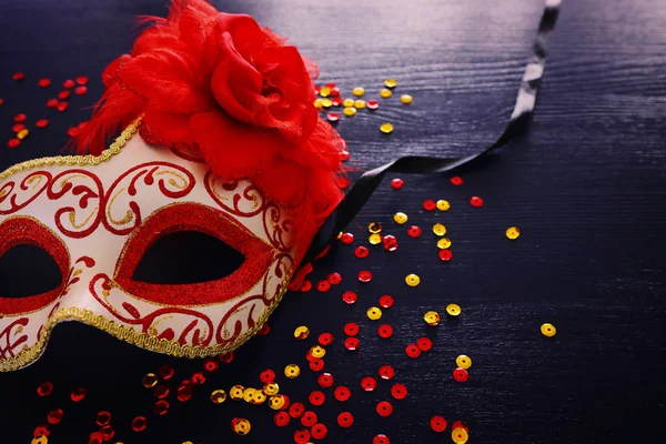 Foto de máscara veneziana vermelha elegante sobre fundo de madeira escura — Fotografia de Stock