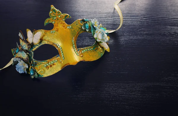Фото изящной и нежной золотой венецианской маски на темном деревянном фоне — стоковое фото