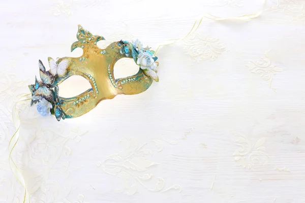 Фото витонченої та делікатної золотої венеціанської маски над білим дерев "яним фоном. — стокове фото