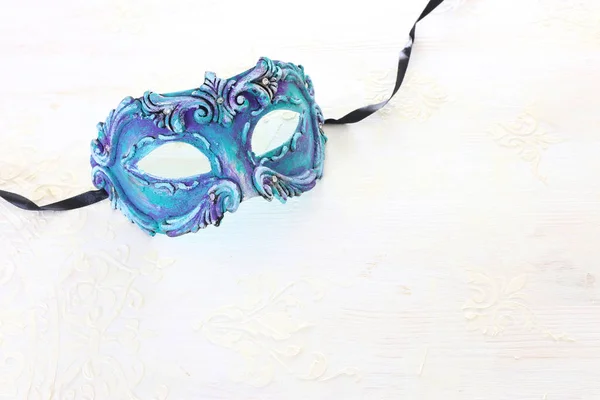 Photo of elegant and delicate blue Venetian mask over white wooden background