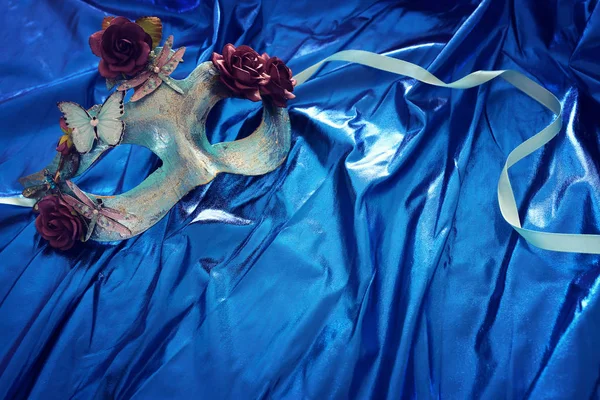 Photo of elegant and delicate Venetian mask over blue silk background — Stock Photo, Image