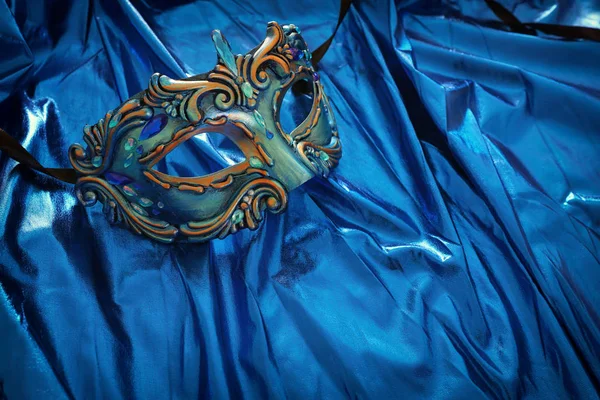 Φωτογραφία από κομψό και λεπτή βενετσιάνικη μάσκα πάνω από μπλε φόντο μετάξι — Φωτογραφία Αρχείου