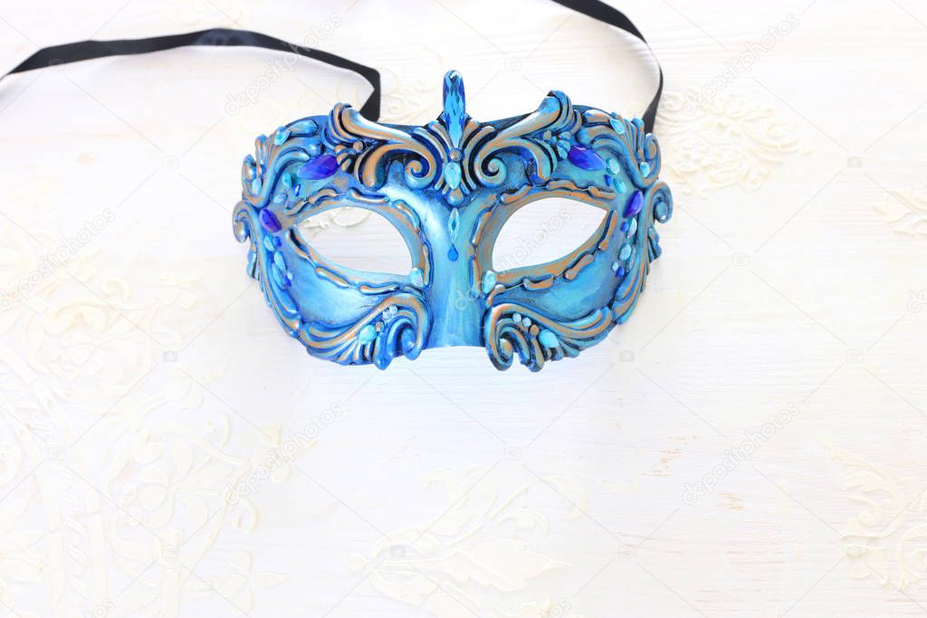 Photo of elegant and delicate blue Venetian mask over white wooden background