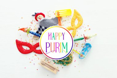 Parti renklendiricisi, maske ve beyaz ahşap arka planda şirin bir palyaço bebeği. Üst manzara, düz uzanma