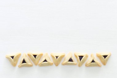 Purim bayramı konsepti (Yahudi karnavalı bayramı). Beyaz ahşap zemin üzerinde Hamantaschen kurabiyeleri