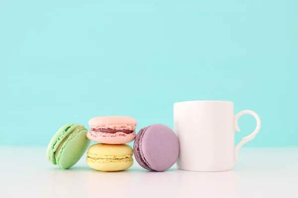 White cup of coffee and colorful macaron or macaroon over pastel wooden table — Stock Photo, Image