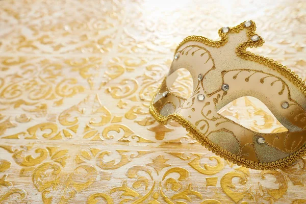 Foto van elegante en delicate Venetiaanse masker over vintage gouden houten achtergrond — Stockfoto