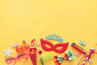 Parti renklendiricisi, maske ve sarı ahşap arka planda şirin bir palyaço bebeği. Üst manzara, düz uzanma