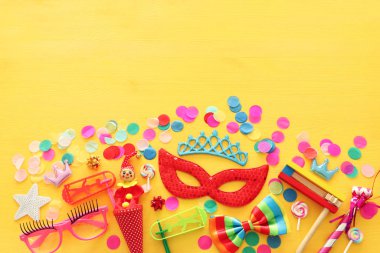 Parti renklendiricisi, maske ve sarı ahşap arka planda şirin bir palyaço bebeği. Üst manzara, düz uzanma