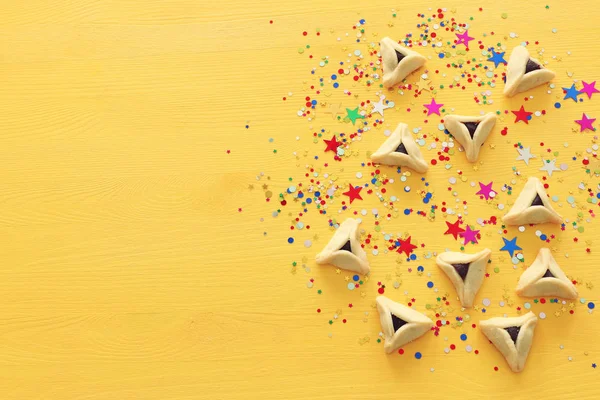 Purim-Feier-Konzept (jüdischer Faschingsfeiertag). Plätzchen über gelbem Holzgrund mit Konfetti — Stockfoto