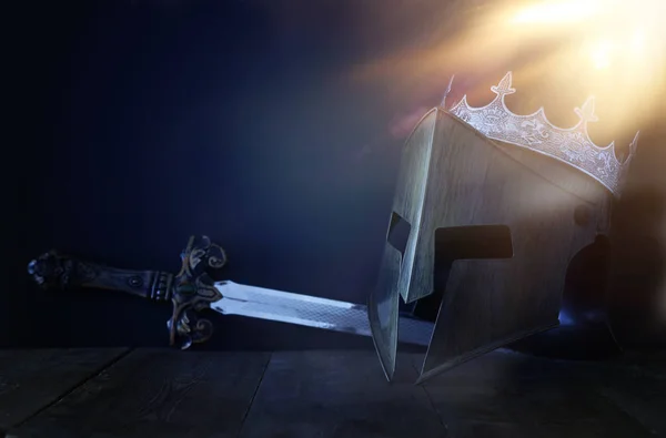 Foto der Krone über König Ritterhelm Rüstung und Schwert über dunklem Hintergrund. Mittelalterliches Konzept — Stockfoto