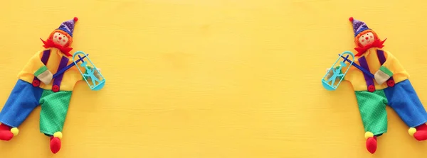 Party kolorowy hałaśliwy i ładny klaun na żółtym drewnianym tle. Widok z góry, płaski — Zdjęcie stockowe