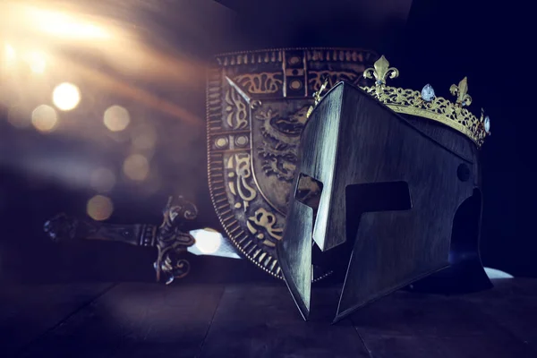 Photo of crown over king knight helmet armor and sword over dark background. Medieval period concept — Stock Photo, Image