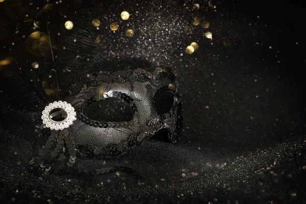Foto von eleganten und zarten schwarzen venezianischen Maske über dunklem Glitzerhintergrund — Stockfoto