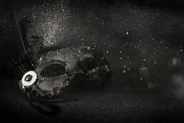 Фото элегантной и нежной черной венецианской маски на фоне темных блесток — стоковое фото