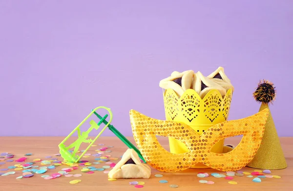 Purim celebration concept (jewish carnival holiday) over purple wooden background — Stock Photo, Image