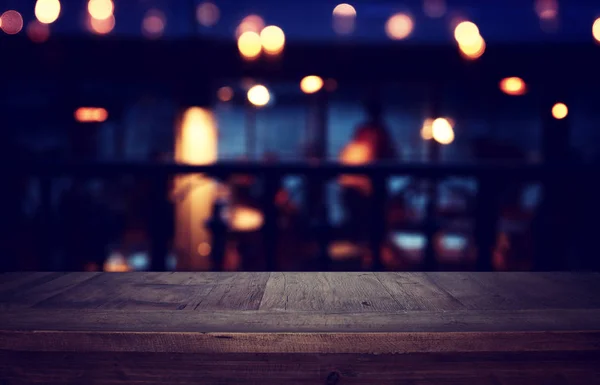 Tło Obraz drewnianego stołu przed abstrakcyjnymi rozmytymi światłami restauracji — Zdjęcie stockowe