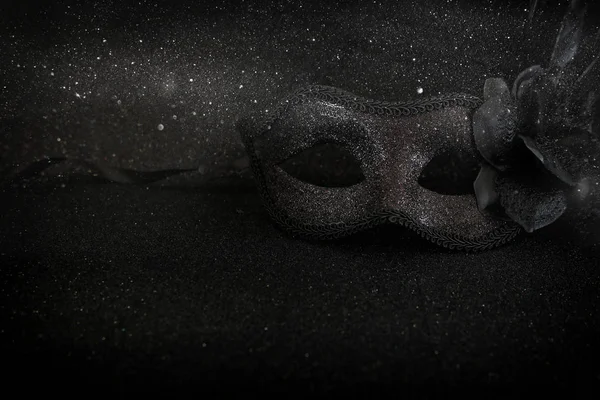 Φωτογραφία από κομψό και λεπτή μαύρη βενετσιάνικη μάσκα σε σκούρο φόντο glitter — Φωτογραφία Αρχείου