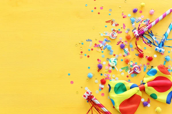 Party kleurrijke confetti over gele houten achtergrond. Bovenaanzicht, vlak lay — Stockfoto