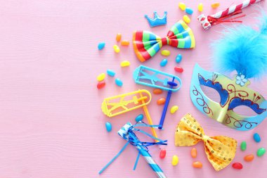 Parti renklendiricisi, maske ve pembe ahşap arka planda şirin bir palyaço bebeği. Üst manzara, düz uzanma