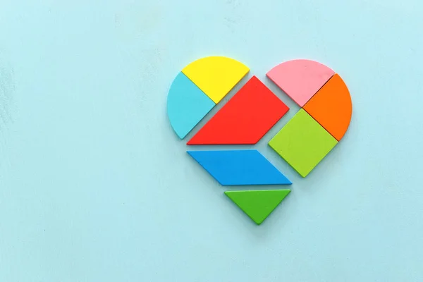 Heart puzzle on blue pastel wooden background