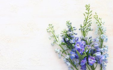 Beyaz, eski, ahşap arka planda bir buket mavi çiçek. Üst görünüm, düz uzanma