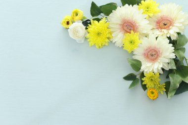 Sarı ve beyaz Gerbera çiçeklerinden oluşan bir buket pastel ahşap arka planda. Üst görünüm, düz uzanma