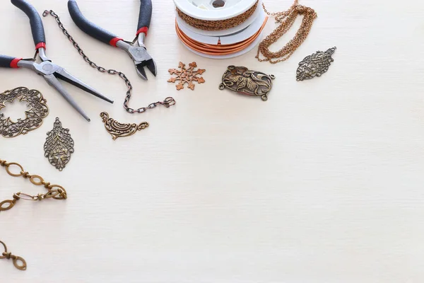 白色木制背景上的黄铜链子 丝状饰物和工具的珠宝制作概念 — 图库照片